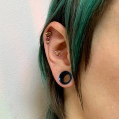 a woman with green hair wearing ear piercings