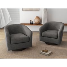 two gray chairs sitting on top of a rug next to a vase and candle holder