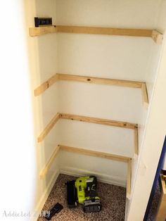 the corner of a room with some tools on the floor next to it and two shelves