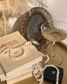 a table topped with jewelry and a wine glass filled with liquid next to a mirror