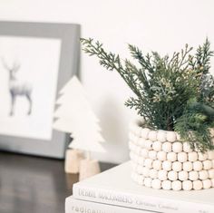 a white basket filled with christmas decorations on top of a table next to two framed pictures