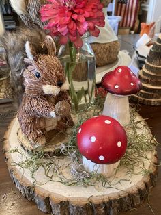 a vase filled with flowers next to two stuffed animals on top of a tree stump