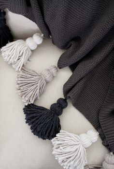 the black and white tasselled necklace is laying on top of a gray sweater