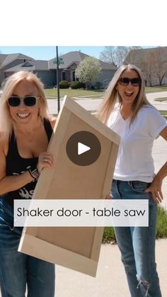 two women standing next to each other holding up a cardboard box with the words shaker door - table saw on it