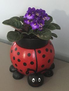 a lady bug planter with purple flowers in it