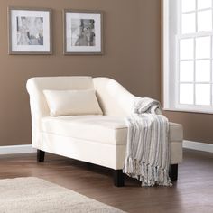 a white couch sitting on top of a hard wood floor next to two framed pictures