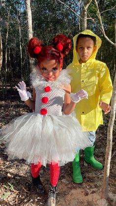 two children dressed up in costumes standing next to each other on the forest floor with trees behind them