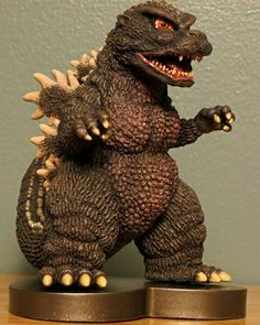 a godzilla figurine sitting on top of a wooden table next to a wall