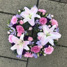 a bunch of flowers that are sitting on the ground in front of some concrete tiles