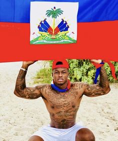 a man sitting on the beach holding up a flag over his head with both hands