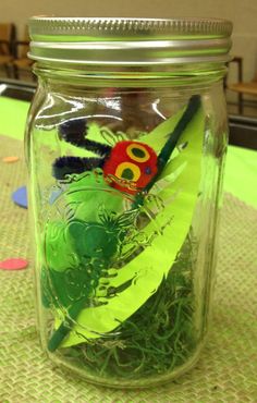 a glass jar filled with green and red feathers