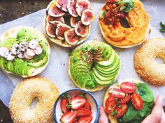 several different types of bagels and pastries on a tray with strawberries, avocado