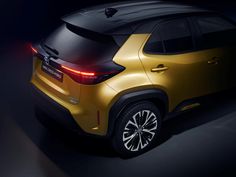 the rear end of a yellow suv in a dark room