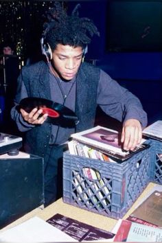 a young man wearing headphones is looking at records in a record box and listening to music