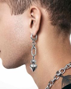 a man with tattoos on his neck wearing a pair of silver chain earrings