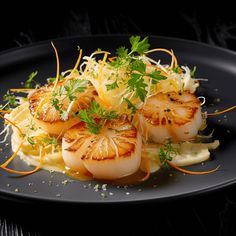 a black plate topped with scallops and garnish