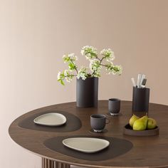 a wooden table topped with plates and cups next to a vase filled with white flowers