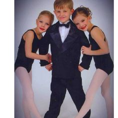 three young ballerinas in tuxedos posing for a photo with their arms around each other