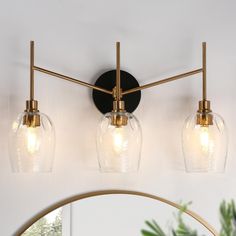 three light bathroom fixture with clear glass globes and gold accents on an oval mirror