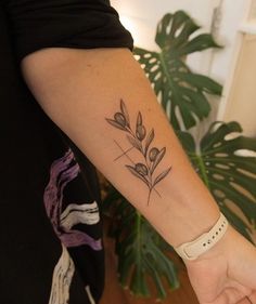 a woman's arm with a tattoo on it and a plant in the background