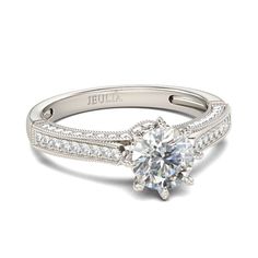 a white gold engagement ring with diamonds on the band and a round brilliant cut center stone