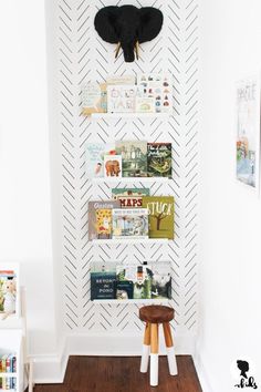 a white wall with some books on it and an elephant head mounted to the wall