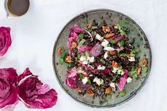 a bowl filled with salad next to flowers and a cup of coffee on a table