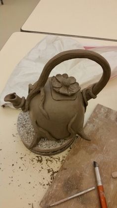 a clay teapot sitting on top of a wooden cutting board