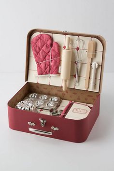 an open suitcase filled with silverware on top of a white table next to utensils