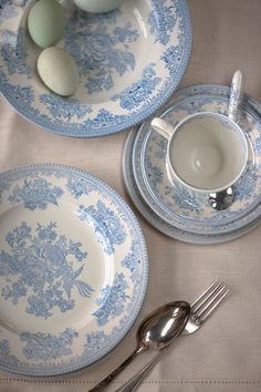 two blue and white plates with spoons, forks and eggs on top of them