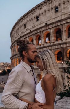 a man and woman standing next to each other in front of the colossion