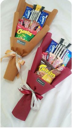 two candy bouquets wrapped in brown paper and tied with ribbon on white bed sheet