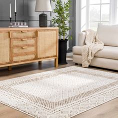 a living room with a white rug and wooden furniture