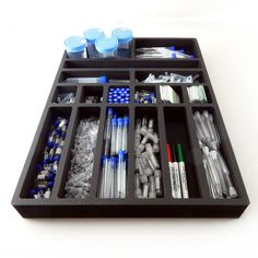 an assortment of toothbrushes and other items in a black tray on a white surface