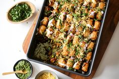 a pan filled with food next to bowls of salsa