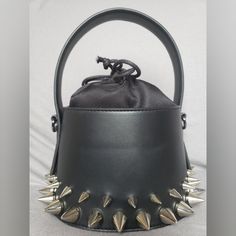 Small, round purse refashioned with three different size silver metal spikes, accompanied by a shoulder strap. A bag that keeps it style whether you are running errands in the day or keeping it sleek and sultry during a night out. Punk Party Bags With Adjustable Strap, Punk Style Party Shoulder Bag With Adjustable Strap, Edgy Party Bags With Metal Hardware, Party Shoulder Bag With Silver-tone Hardware, Bucket Shape, Party Bucket Shoulder Bag With Silver-tone Hardware, Punk Style Party Bag With Rivets, Punk Style Party Bags With Rivets, Punk Party Shoulder Bag With Rivets, Punk Party Bag With Rivets