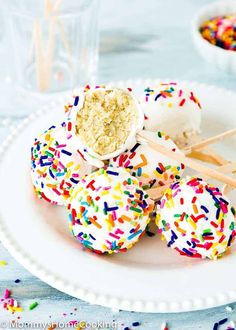 sprinkle covered donuts on a white plate with toothpicks in the middle