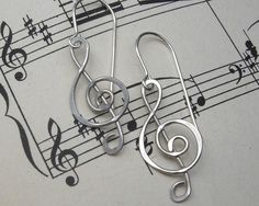 pair of silver musical notes earrings on sheet music note background with black and white trebles