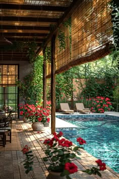 an outdoor dining area next to a pool with red flowers on the table and chairs