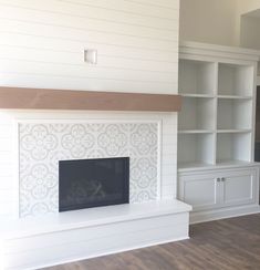 an empty living room with a fireplace and built - in bookcases