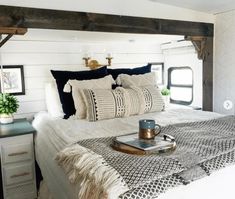 a bed with pillows and blankets on top of it in a room that has white walls