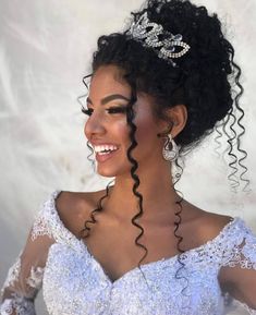 a woman with curly hair wearing a tiara and smiling at the camera while standing in front of a white backdrop