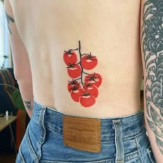 a woman with tattoos on her stomach has tomatoes drawn on her back and is holding a piece of wood