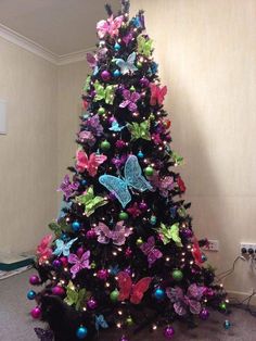 a decorated christmas tree with purple, green and blue butterflies on it's top