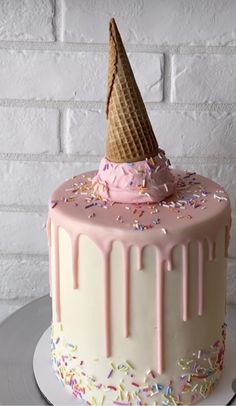 a birthday cake with an ice cream cone on top and sprinkles all over it