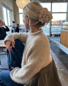 a woman sitting on a chair with her hair in a pony tail bun and jeans