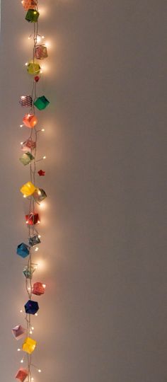 a string of lights hanging from the side of a white wall with multiple colored lamps attached to it