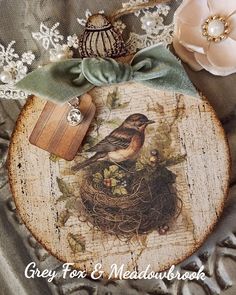 a bird sitting on top of a wooden plaque next to flowers and a ribbon tied around it