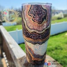 a cup sitting on top of a wooden table in front of a green grass field