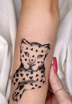 a tattoo on the arm of a woman with a cheetah head and hearts